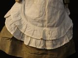 an antique doll of a woman in a white dress and hat