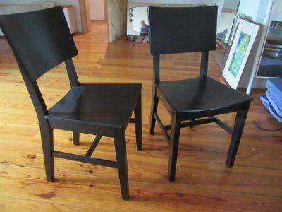 deux chaises noires placées l'une à côté de l'autre sur un parquet en bois massif