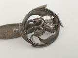 a silver brooch that has a dragon on it