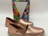 a pair of women ' s metallic slippers with a box in the background