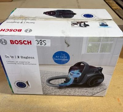 un carton contenant un aspirateur posé par terre devant une fenêtre