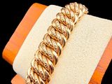 gold plated bracelet on a wooden stand with a black background