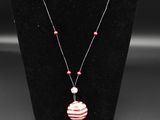 un collier orné d'une perle rayée rouge et blanche sur un mannequin noir
