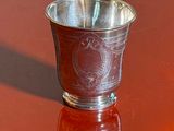 a silver cup sitting on a table with a red background
