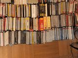 a lot of dvds stacked on a shelf next to a person ' s feet