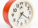 a red and white alarm clock on a white background