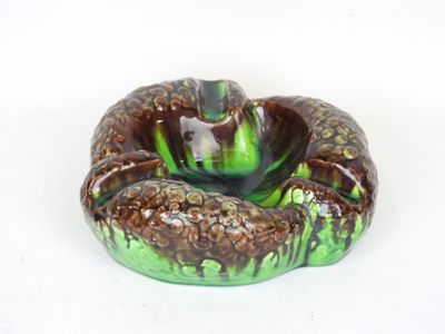 a green and brown glass ashtray on a white surface