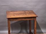 an old wooden table on a parquet floor against a grey wall