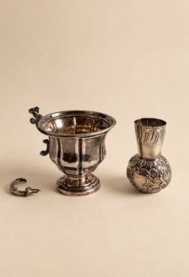 une coupe en argent et un vase en argent posés sur une table