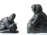 two statues of a man and a woman sitting on a rock