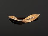 a close up of a gold leaf brooch with diamonds