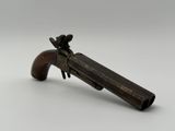un vieux pistolet jouet avec une crosse en bois posé sur une surface blanche