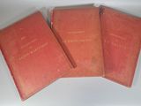 trois livres rouges posés sur une table blanche