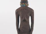 an image of a wooden statue of a person with a beaded neck