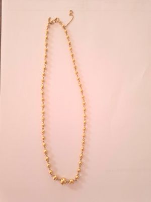 un collier de perles dorées posé sur une feuille de papier