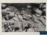 black and white photograph of a group of people sitting on a rock