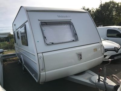 une petite caravane blanche garée sur un parking