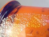 un gros plan d'un vase orange parsemé de petites taches blanches