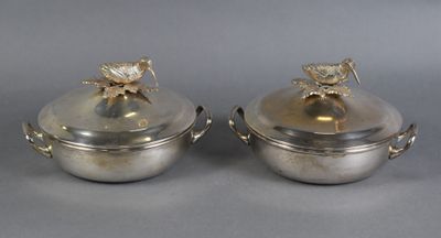 two silverplated dishes with lids and handles on a gray surface
