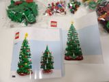 several lego christmas trees are displayed on a table in front of a book
