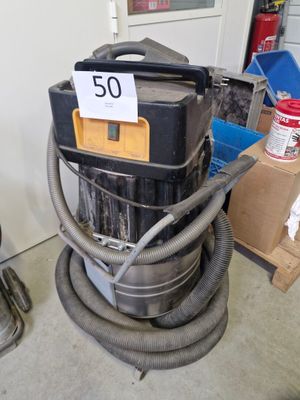 un aspirateur posé dans une pièce, sur lequel est accrochée une pancarte