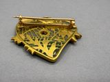 gold plated broochle with a green and white design on it