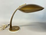 a gold desk lamp on a white surface with a cord
