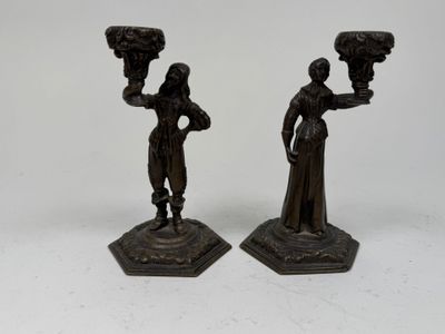 pair of bronze figurines of a woman and a man holding a vase
