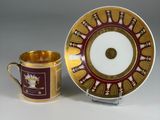 an antique cup and saucer with a gold rim and a red and white plate