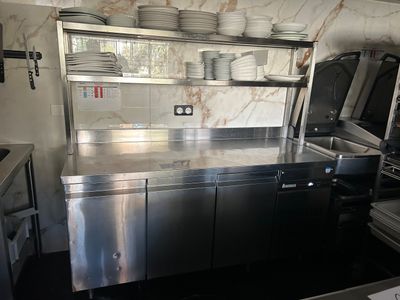 une grande cuisine en inox avec beaucoup de vaisselle sur le plan de travail