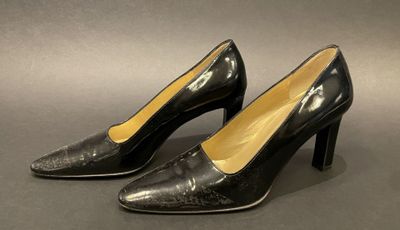 a pair of black high heeled shoes on a gray surface