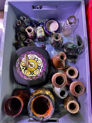 de nombreux vases de toutes sortes dans une boîte violette posée par terre