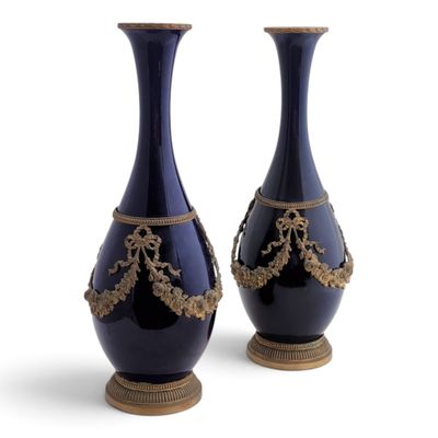une paire de vases bleus ornés de motifs dorés, posés sur des socles, sur fond blanc