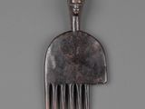 a metal comb with a face on it on a gray surface
