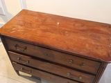 a wooden chest of drawers in the corner of a room