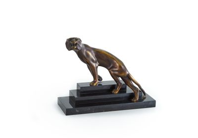 La statue en bronze représentant un chien est posée sur un socle noir.
