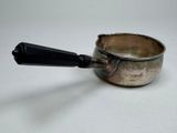 a small silver pot with a black handle on a white table