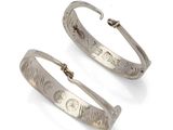 pair of silver hoop earrings with engraved designs on them