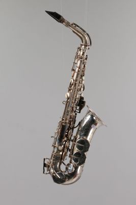 a close up of a saxophone hanging from a string on a wall