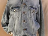 une veste en jean posée sur un support de mannequin, dans une vitrine de mannequins