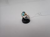 un gros plan d'une bague sertie d'une topaze bleue sur un support noir