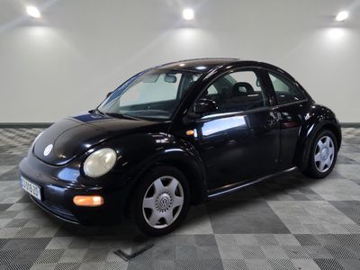une photo d'une Coccinelle Volkswagen noire garée sur un sol à damier