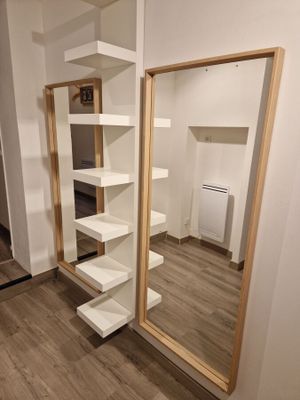 a large mirror in the corner of a room with shelves