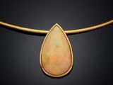a yellow gold necklace with an oplite tear pendant on a black background