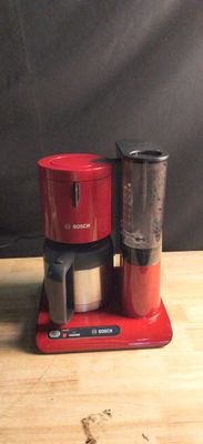 a red coffee maker sitting on top of a wooden table