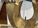 brass sculpture of a bird on a glass table with a mirror in the background