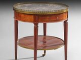une petite table ronde avec un plateau en marbre, montée sur roulettes