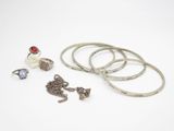trois bagues, un bracelet et une bague ornée d'une pierre rouge sur un fond blanc