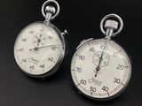 two clocks that are sitting on a black surface