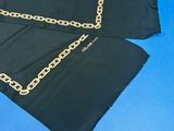 black scarf with gold chains on it laying on a blue surface